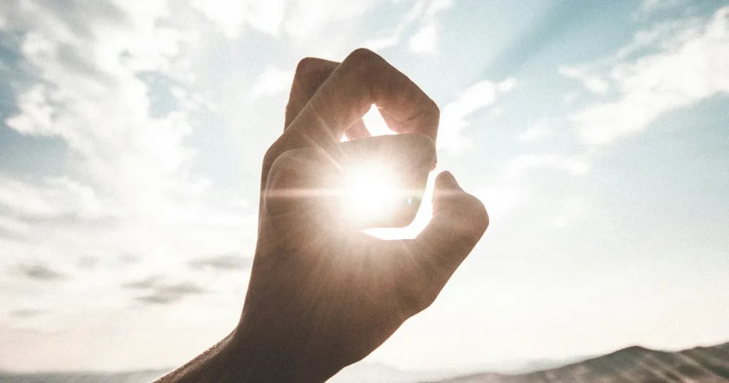 幸せについて記事の内容を、太陽の光を手で掴もうとしている写真で表現