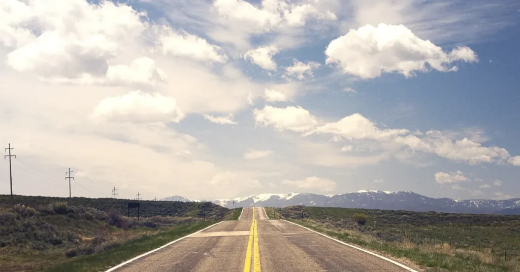A wide road stretches out under a clear blue sky.