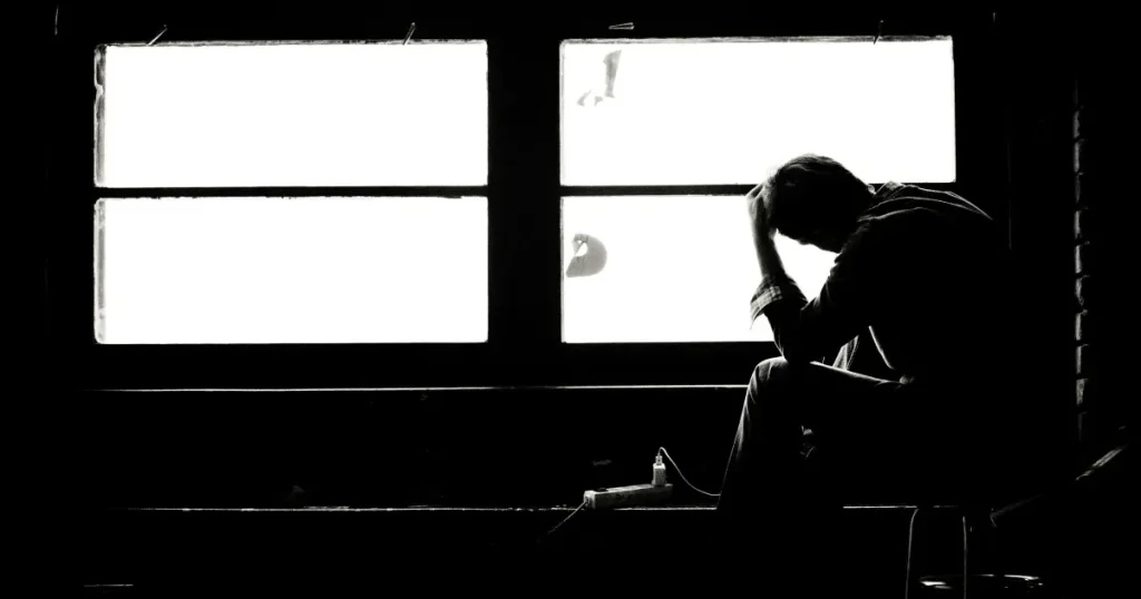 消防活動での挫折を1人の男性が暗い部屋で頭を抱えている画像で表現